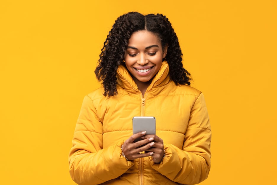 Cheerful Black Lady With Cellphone Using Mobile App In Studio